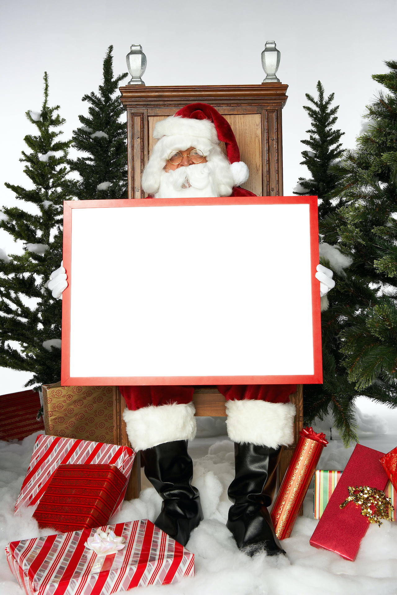 Portrait of Santa sitting on his chair surrounded by presents holding a large canvas